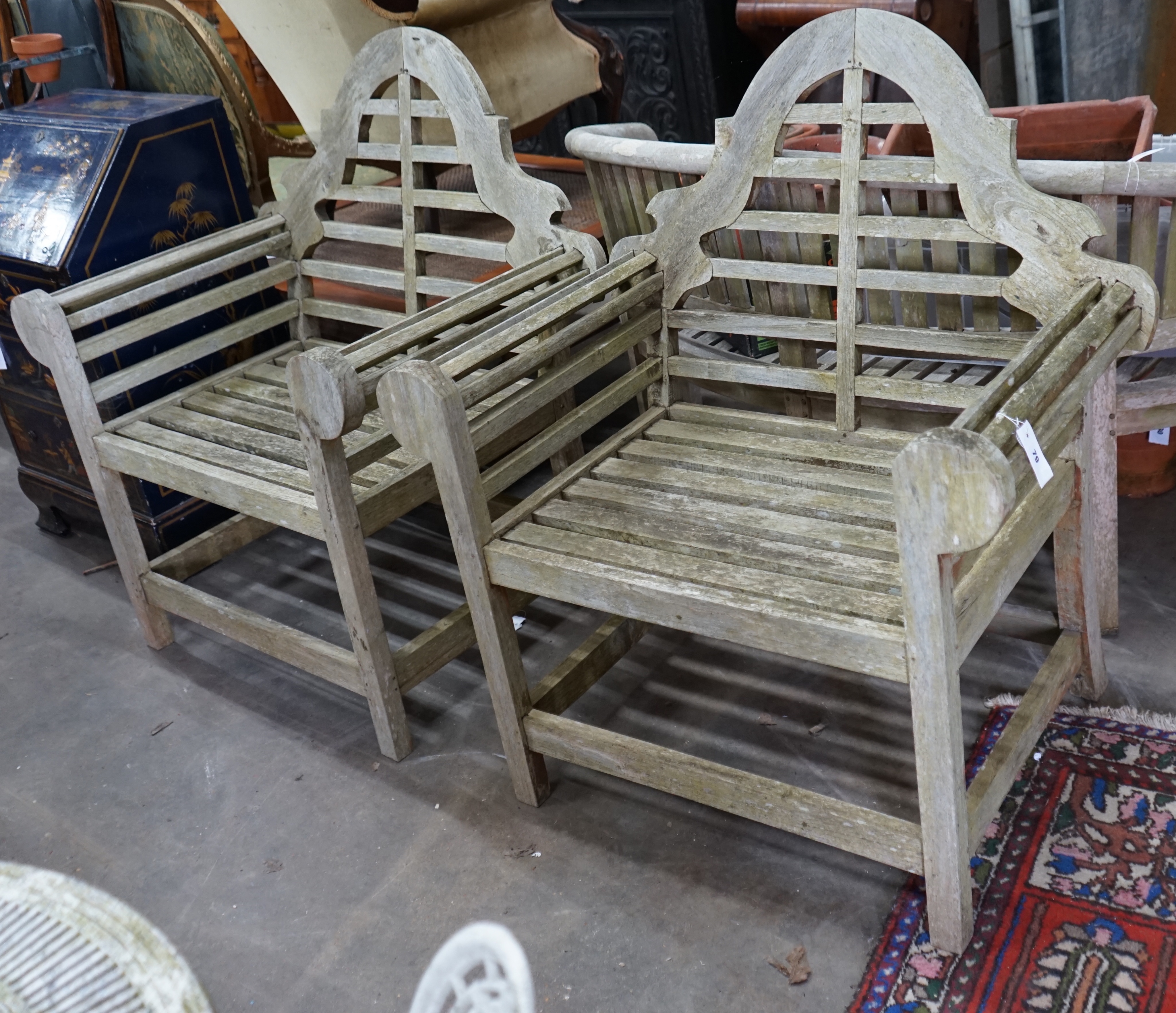 A pair of Lutyens style weathered teak garden armchairs, width 90cm depth 54cm height 105cm